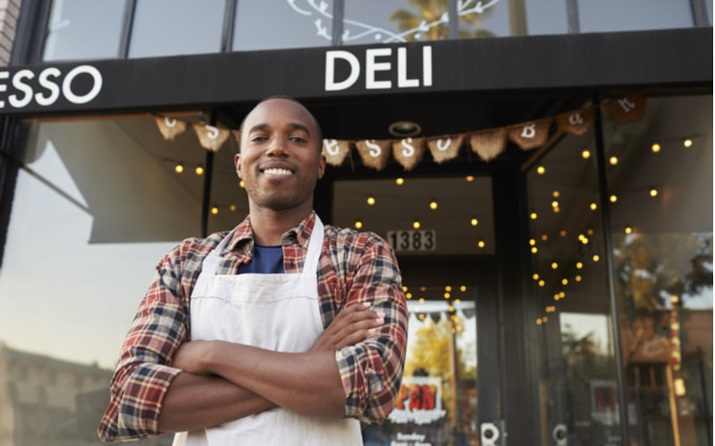 Male business owner standing outside of his deli