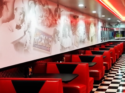 Incredible Pizza Co. graphic on interior wall surrounded by red booths