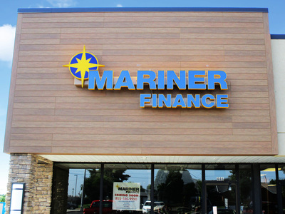 Mariner Finance sign with blue letters displayed on wooden billboard