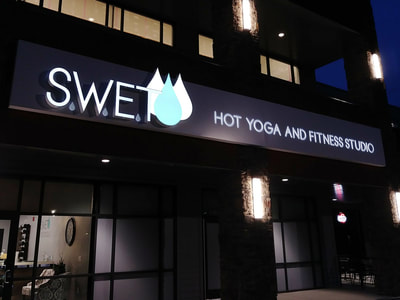 S.W.E.T. Hot Yoga and Fitness black, white, and turquoise sign.